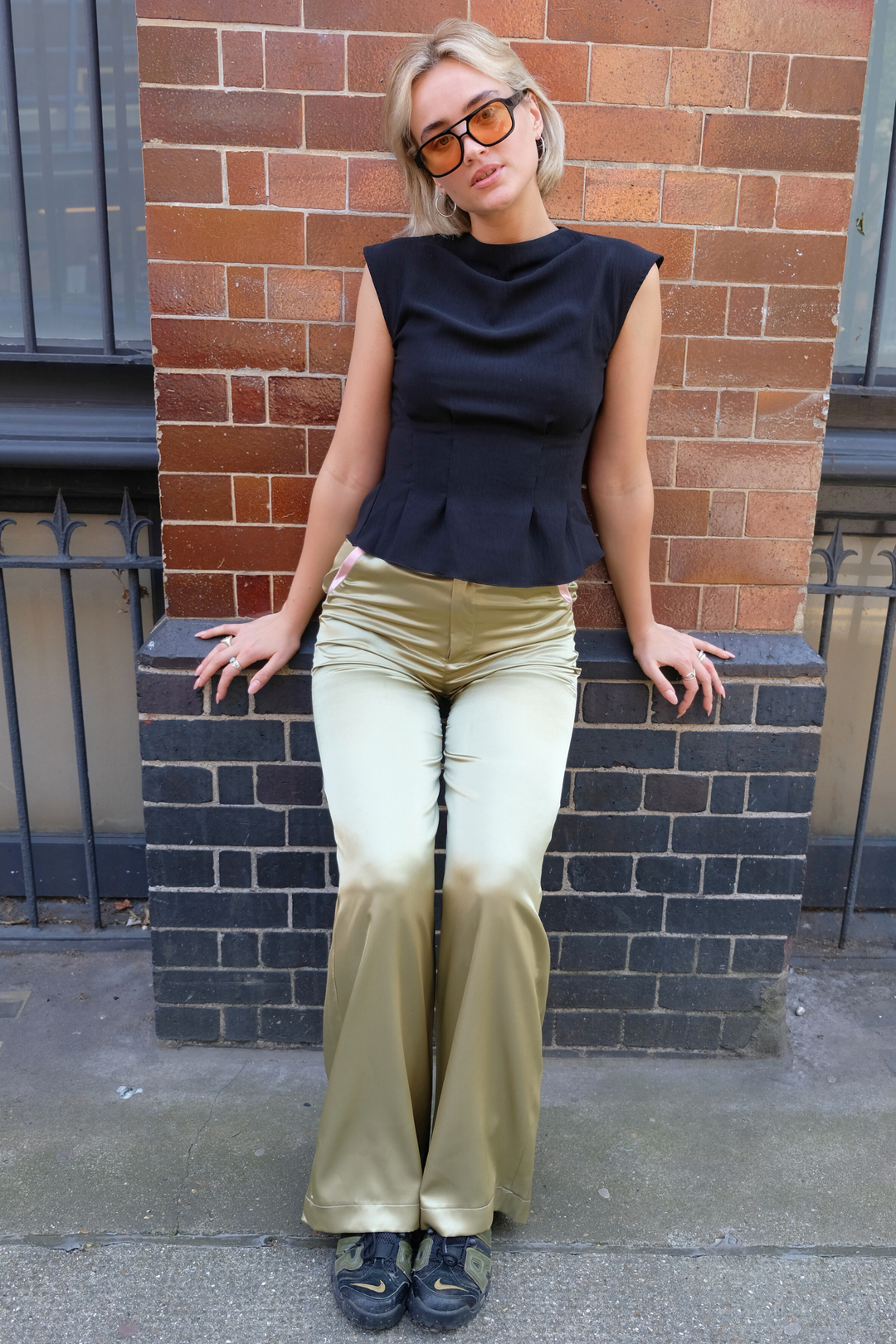 Olive wide-leg silk trousers with pale pink trims, worn in London